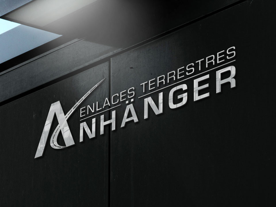 Anhanger-Portafolio-Logotipo-1 Logotipo metálico de la empresa Enlaces Terrestres Anhänger colocado sobre una pared negra, con letras plateadas que destacan el nombre de la empresa.