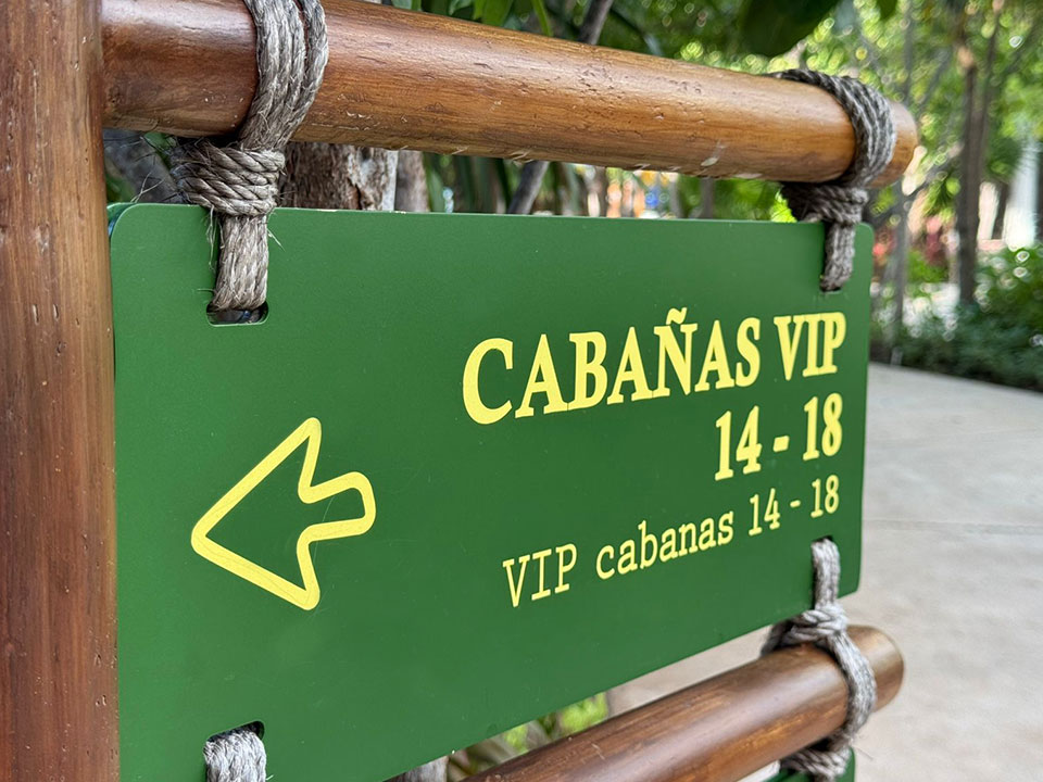 Jungala-Park-Portafolio-Detalle-Direccional Señalética verde con la indicación de las Cabañas VIP 14-18 en Jungala Aqua Experience, con una flecha hacia la izquierda, montada sobre un soporte de madera.