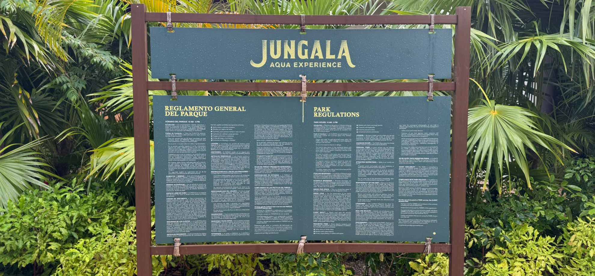 Jungala-Park-Portafolio-Reglamento Señalética de Jungala Aqua Experience mostrando el reglamento general del parque en un panel verde, rodeado de vegetación tropical, con texto en español e inglés.