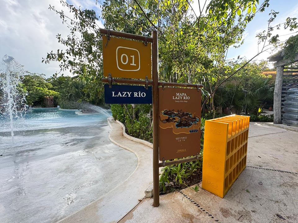 Jungala-Park-Portafolio-Rio-Lento Señalética del punto de inicio '01' del 'Lazy Río', una atracción de río lento en Jungala Aqua Experience, junto a un mapa de la instalación y una zona de almacenaje de flotadores.