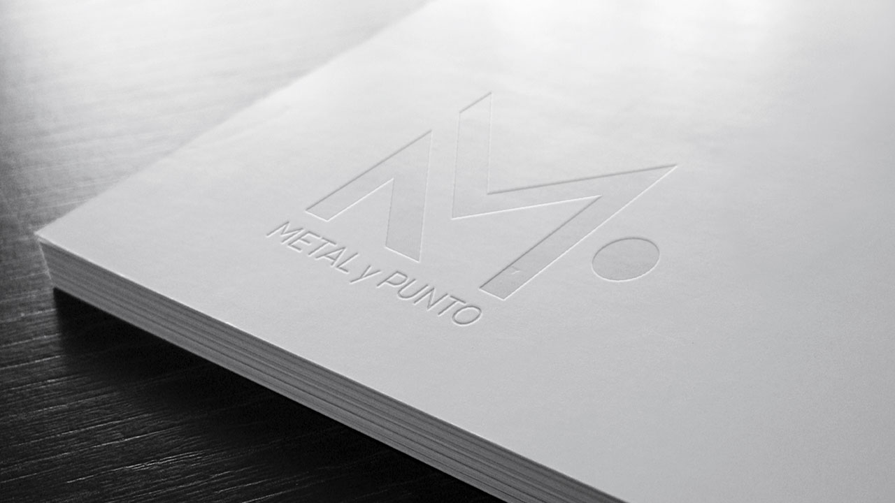 MetalyPunto-Portafolio-Logotipo-2 Logotipo de la marca Metal y Punto en relieve sobre una carpeta o cuaderno blanco. El logotipo está diseñado con líneas simples y elegantes.