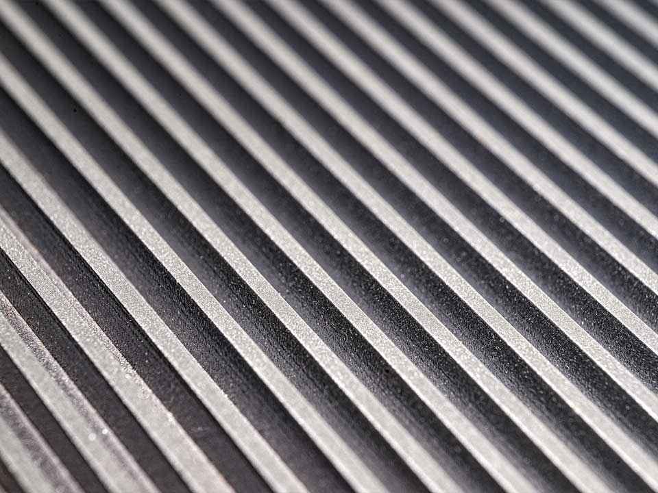 MetalyPunto-Portafolio-Metal Imagen cercana de una superficie metálica acanalada en tonos grises.